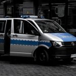 Van policial estacionada em uma rua urbana de paralelepípedos.
