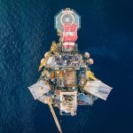 Vista aérea de uma plataforma de petróleo offshore cercada pelo oceano.