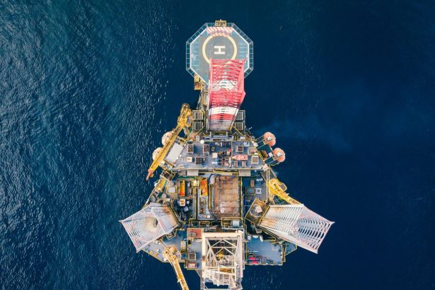 Vista aérea de uma plataforma de petróleo offshore cercada pelo oceano.