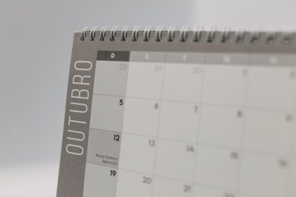 Close de um calendário de mesa aberto no mês de outubro, com encadernação espiral.