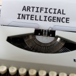 Máquina de escrever com as palavras “ARTIFICIAL INTELLIGENCE” em uma folha de papel.