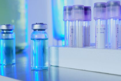 Frascos e tubos de ensaio com líquido azul em um laboratório iluminado por luz fluorescente