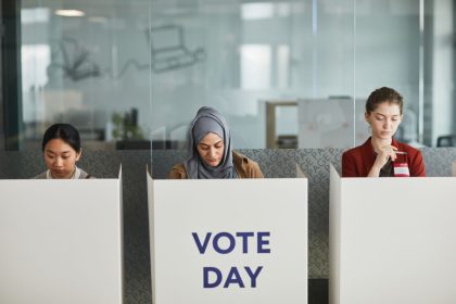 Três mulheres votam em cabines individuais durante uma eleição.